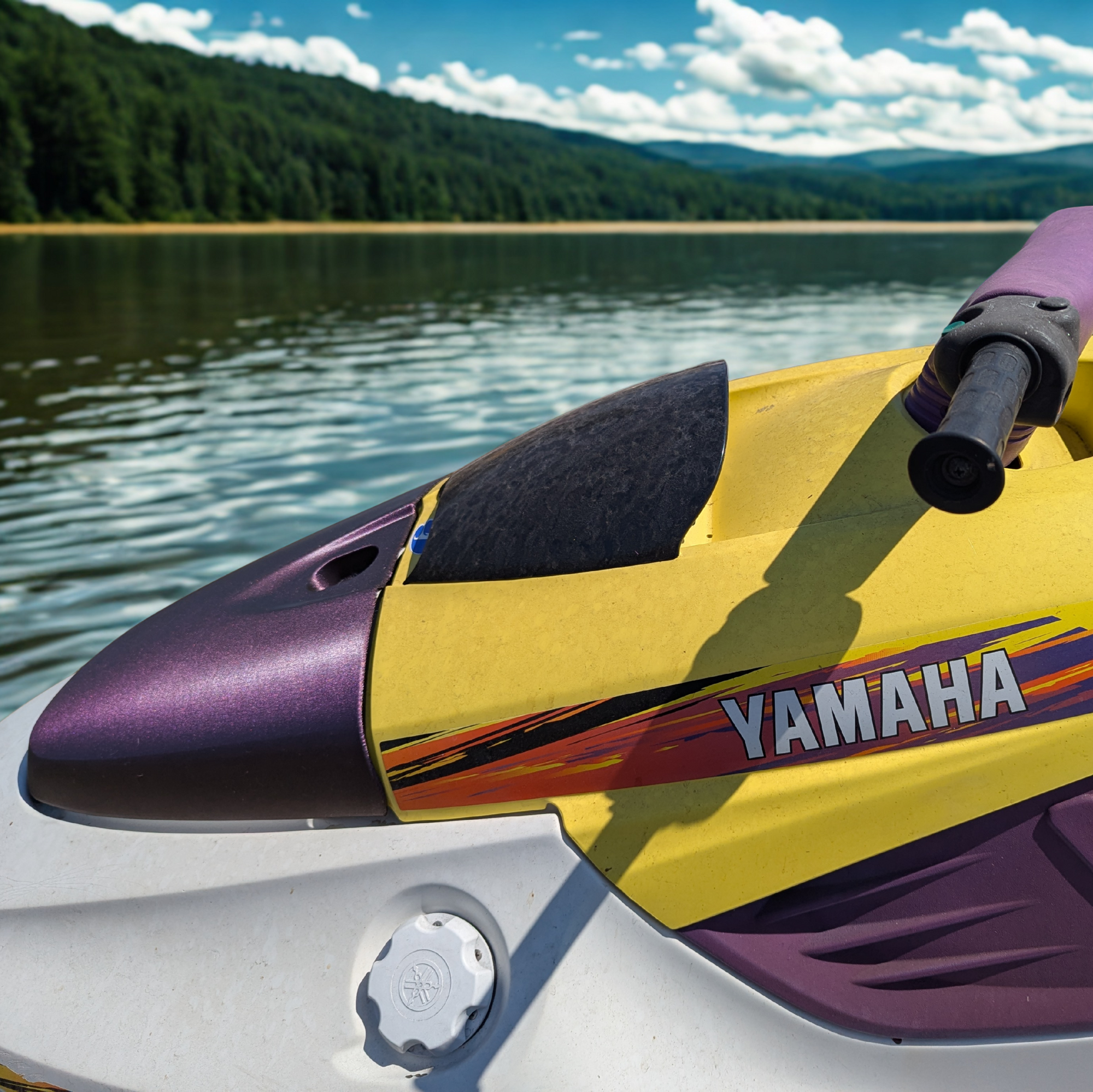 Close-up of a Yamaha Wave Blaster watercraft on a lake with mountains in the background and a new hood. made by Quenchifying